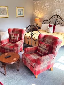 Luxury Bedrooms with iron frame bed and two tartan armchairs