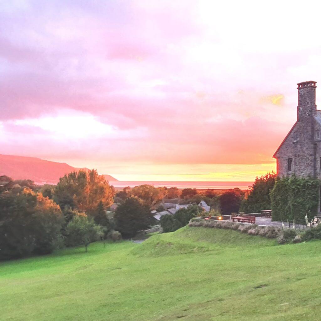 Sunset view from the garden looking towards the sea and bay of Porlock, with Bossington Hall in the foreground